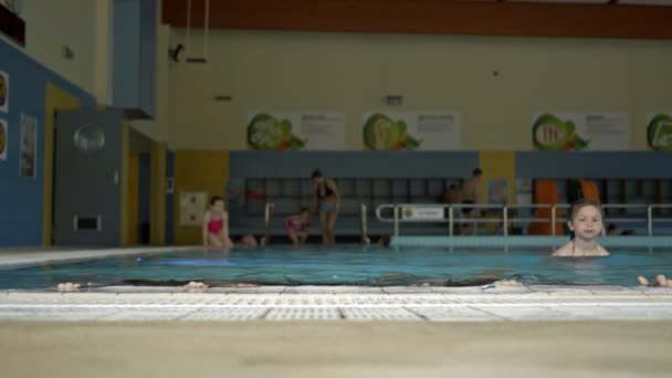 Uma jovem e duas adolescentes saem da piscina. A menina nada com eles. Fim de semana divertido . — Vídeo de Stock