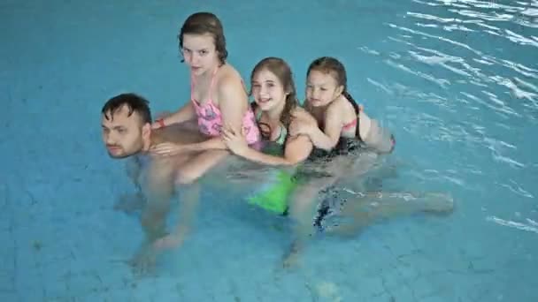 Homem de meia-idade joga na piscina com suas três filhas. Feliz fim de semana . — Vídeo de Stock