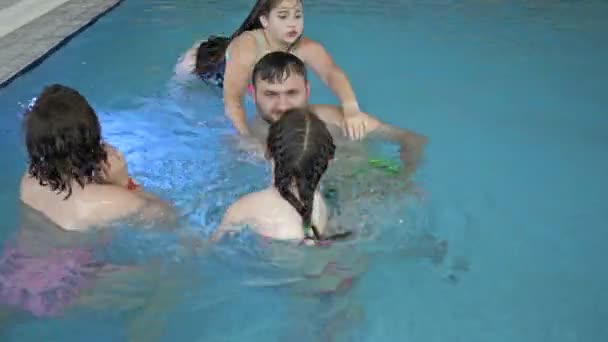 Homem de meia-idade joga na piscina com suas três filhas. Feliz fim de semana . — Vídeo de Stock