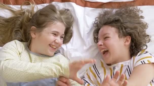 Deux copines adolescentes sont couchées au lit et s'amusent ensemble.