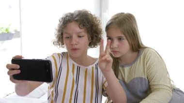 Pijama partisi. İki genç kız arkadaş cep telefonlarıyla yatakta oturuyor ve bloglarında komik haberler paylaşıyorlar..