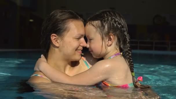 Porträtt av en ung kvinna med en liten dotter i poolen. — Stockvideo