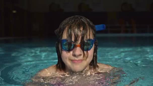 Portrait d'une adolescente avec des lunettes pour la natation proviennent de l'eau de la piscine. — Video