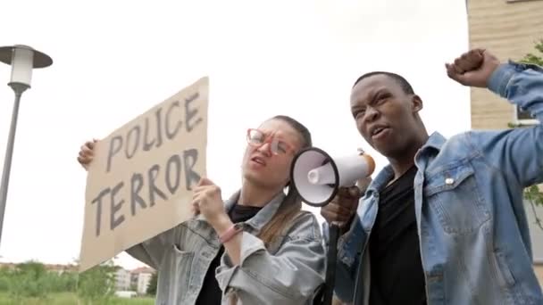 Протест против расизма. Девушка в очках размахивает баннером с надписью "Полицейский ужас". Вместе с черным они скандируют лозунги протеста . — стоковое видео