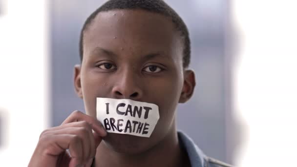 De donkere man rukt een sticker af met de inscriptie I CANT BREATHE van zijn lippen en zucht met opluchting. — Stockvideo