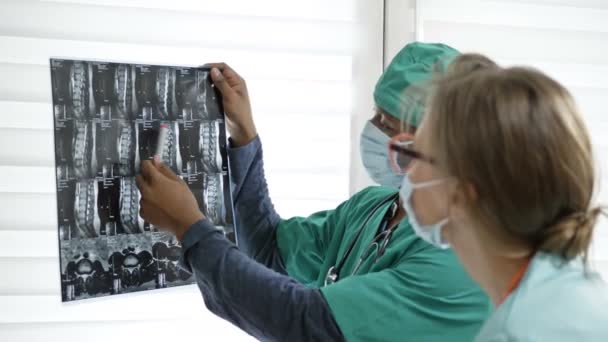 Deux médecins examinant des images radiographiques de patients pour le diagnostic. Concept de l'absence de contradictions interraciales dans une équipe de professionnels. — Video