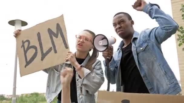 Irkçılığa karşı protesto. BLM pankartı sallayan gözlüklü kız. Siyahi adamla birlikte protesto sloganları atıyorlar.. — Stok video