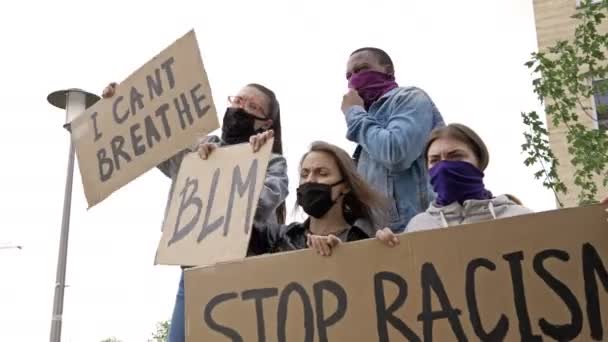 Grupo de jóvenes con máscaras oscuras sostiene carteles PARAR EL RACISMO, NO PUEDO BREATHE, BLM. Están coreando consignas de protesta . — Vídeo de stock