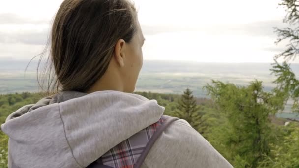 Kvinna med ryggsäck står på toppen och beundrar skönheten i en bergsdal. Flickan reser till vackra platser. Vackert landskap. — Stockvideo