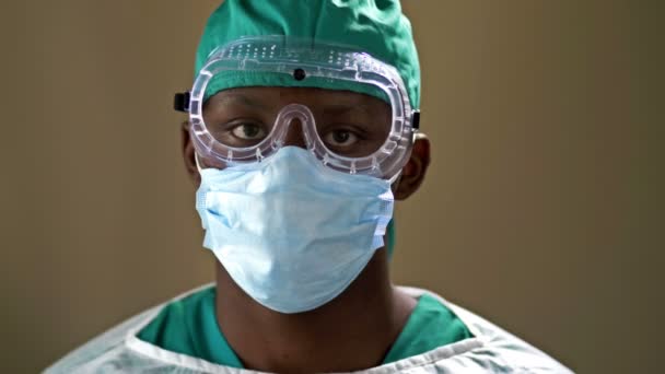 A fiatal afrikai orvos sebészeti maszkot és védőszemüveget visel. Koronavírus. Pandémia. Egészségügyi ellátás. — Stock videók
