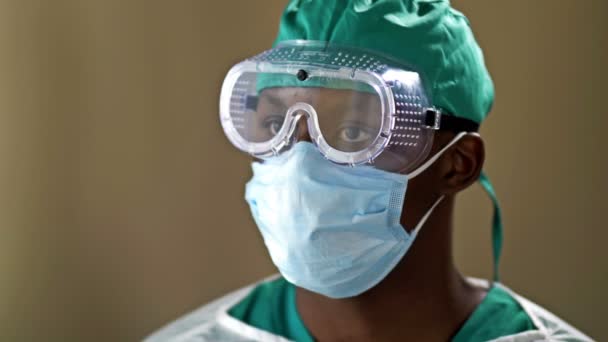 Jeune médecin africain portant un masque chirurgical et des lunettes de protection. Coronavirus. Une pandémie. Soins de santé. — Video