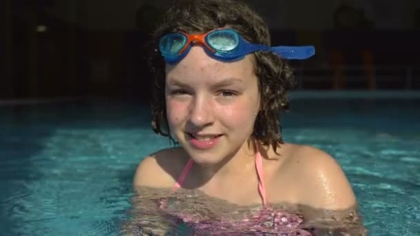 Retrato de uma adolescente com óculos para nadar vêm da água da piscina . — Vídeo de Stock