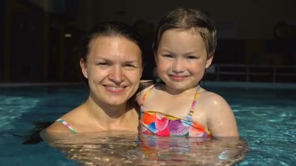 Retrato de una joven con una hija pequeña en la piscina . — Vídeos de Stock