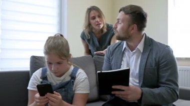 Aile içinde ebeveynlik sorunları. Ebeveynler genç bir kızı bir şey için azarlıyorlar. Kız telefon ekranına dikkatsizce bakıyor ve ailesini daha da kızdırıyor..