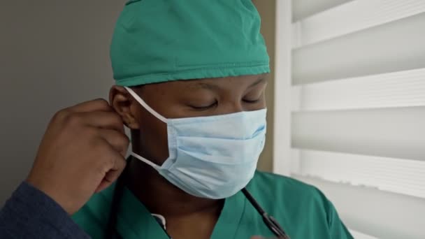 Cansado jovem médico de pele escura tira uma máscara médica e suspira em alívio. A recepção acabou. . — Vídeo de Stock