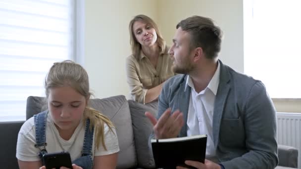 Probleme der Elternschaft in der Familie. Eltern schimpfen sehr auf eine Teenagertochter für etwas. Das Mädchen blickt gleichgültig auf den Telefonbildschirm und verärgert ihre Eltern noch mehr. — Stockvideo