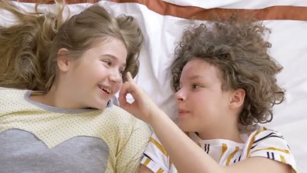 Une soirée pyjama. Deux amis adolescents sont couchés au lit avec des téléphones mobiles et partagent des nouvelles drôles.