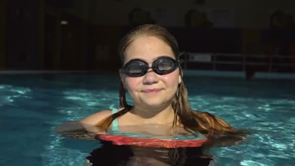 Portrait d'une adolescente avec des lunettes pour la natation proviennent de l'eau de la piscine. — Video