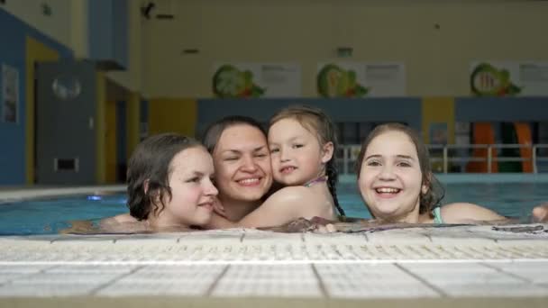 Vacaciones familiares en la piscina. Mujer joven y tres chicas se divierten en la piscina . — Vídeo de stock