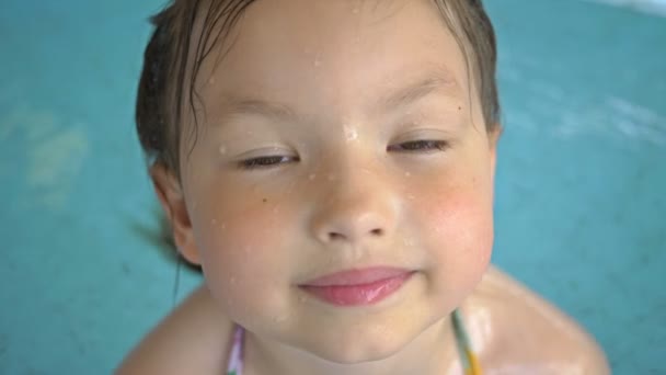 Porträt eines kleinen Mädchens, das in einem Hallenbad schwimmt. Aktive Freizeitgestaltung im Wasserpark. Glückliches Kind. — Stockvideo