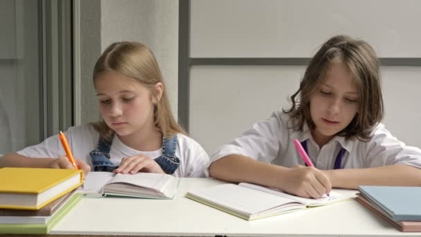 Oğlan ve bir kız aynı masada oturuyorlar. Gençler öğrenme sürecinde aktif olarak yer alıyorlar. — Stok video