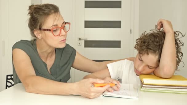 Det är svårt för en pojke att lära sig en läxa. Mamma eller handledare hjälper eleven att göra sina läxor. Svårigheter med hemundervisning. — Stockvideo
