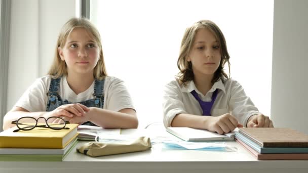 Ragazzo e ragazza seduti allo stesso tavolo in classe indossano maschere mediche. Misura necessaria durante l'epidemia di coronavirus. — Video Stock