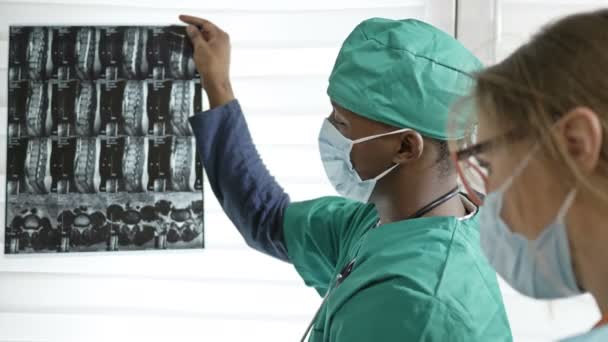 Un jeune médecin à la peau foncée donne des directives à une infirmière. Notion d'absence de contradictions interraciales. — Video