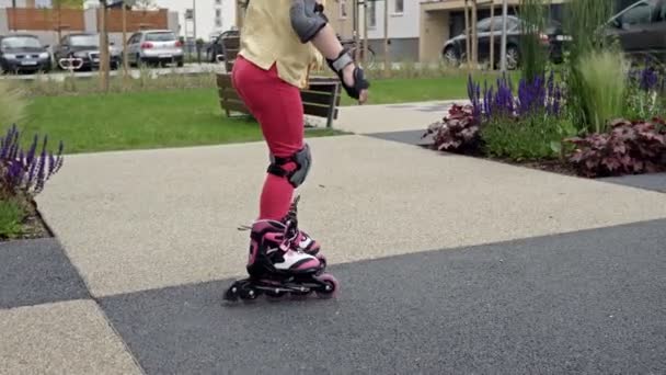 少女はアパートの中庭でローラースケートを学ぶ。彼女は一生懸命しようとするが落ちる. — ストック動画