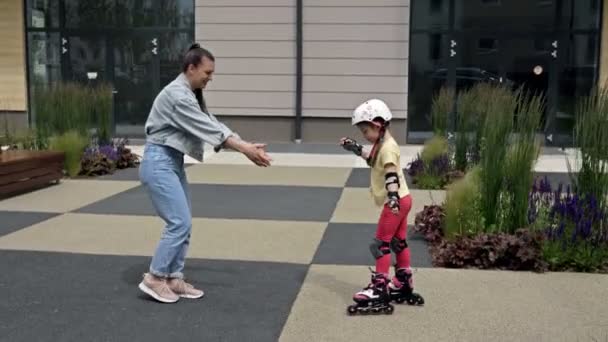 Maman apprend à sa fille à patiner à roulettes. Un passe-temps amusant et gratifiant. — Video