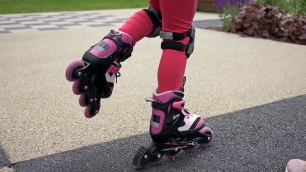 Een kind op rolschaatsen aarzelt lange tijd om de eerste stap te zetten. Dan valt hij en lacht.. — Stockvideo