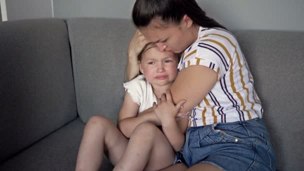 Küçük kız annesinin yanında ağlıyor ve kafasına nazikçe dokunarak teselli veriyor. Çocuğun annesinin anlayışına ihtiyacı var.. — Stok video