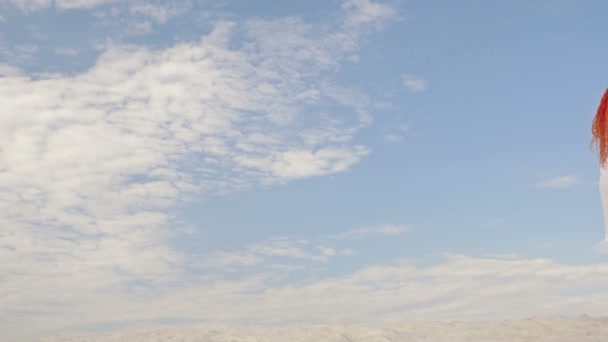 Några älskare omfamnar och beundrar landskapet. Mot bakgrund av vit sand, blå himmel och vita moln. Bakifrån. — Stockvideo