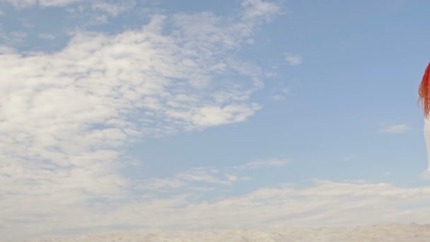 Un par de amantes están abrazando y admirando el paisaje. Sobre el fondo de arena blanca, cielo azul y nubes blancas. Vista trasera. — Vídeo de stock