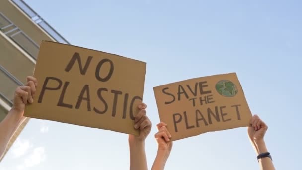 女性の手のポスターを保持している地球を救うとプラスチックなし。澄んだ青空を背景に. — ストック動画