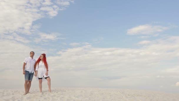 Coppia innamorata stare sulla sabbia bianca contro il cielo blu in nuvole bianche. Appuntamento romantico. — Video Stock