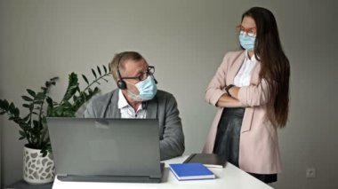 Yaşlı bir ofis çalışanı ve genç bayan meslektaşı mevcut sorunları tartışıyorlar. Covid-19 salgını sırasında ofis işi..