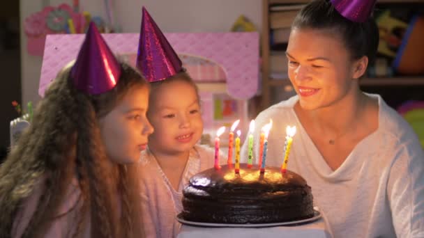 Mutlu küçük kız doğum gününü ailesiyle kutlar, annesi ve genç kız kardeşi mumları söndürmeye yardım eder. — Stok video