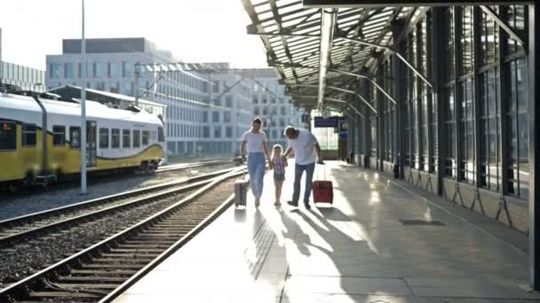 Um homem idoso com sua filha e pouco vuchka estão andando ao longo da plataforma. Os passageiros estão a guardar malas. Bom humor.. — Vídeo de Stock