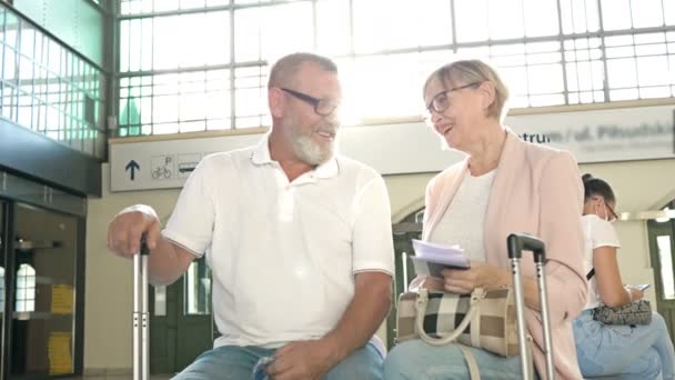 Veselý starší manželé čekají na svůj let v čekárně. — Stock video