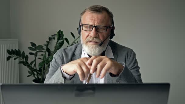 एक वृद्ध माणूस कर्मचारी संगणक गॅझेट वापरुन ऑनलाइन परिषदेत व्यस्त बोलतो. संप्रेषण संकल्पना . — स्टॉक व्हिडिओ