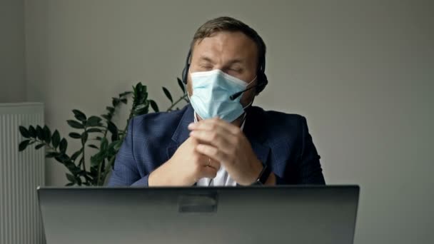 Trabajo durante la epidemia de coronavirus. Un hombre de negocios de mediana edad con alivio se quita la máscara médica al final de la jornada laboral. — Vídeos de Stock