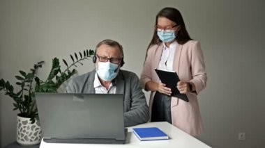 Covid-19 salgını sırasında ofis işi. Genç çalışan yöneticiye sorunları çözmede yardım eder.