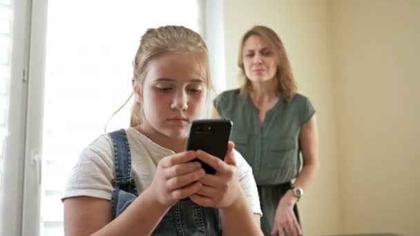 Mutter ist empört, dass ihre halbwüchsige Tochter auf ihrem Handy zuschaut. Sie nimmt das Telefon von ihrer Tochter. Probleme der Beziehung zwischen Eltern und Kindern. — Stockvideo
