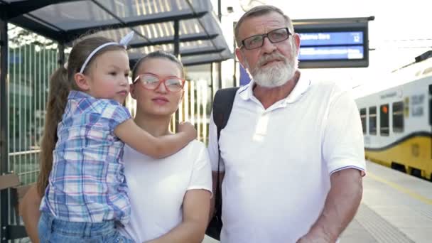 Mujer joven, su padre y su hija pequeña están esperando su tren en la estación. — Vídeos de Stock