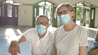 Yaşlı bir çift bekleme odasında uçuşlarını bekliyor. - Ne? Yüzlerinde tıbbi maskeler var. Seyahat, Coronavirus salgını sırasında turizm.