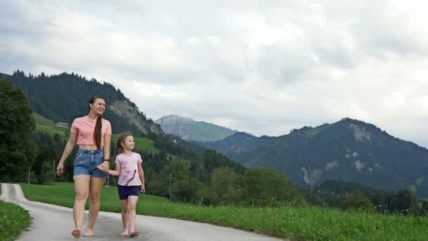 Mujer joven y su hija pequeña están caminando descalzos en una pintoresca zona de montaña y admirar la hermosa vista de los Alpes suizos. — Vídeo de stock