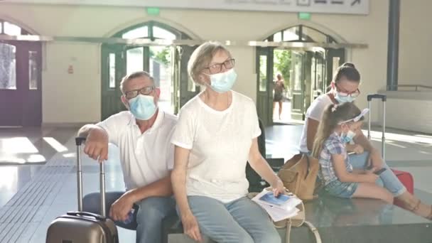 Grupa pasażerów czeka na lot w poczekalni. Każdy ma maski medyczne na twarzy. Podróże, turystyka podczas epidemii koronawirusów. — Wideo stockowe