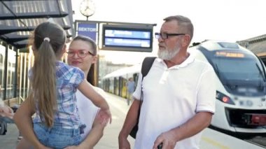 Genç bayan, babası ve küçük kızı istasyonda trenlerini bekliyorlar..