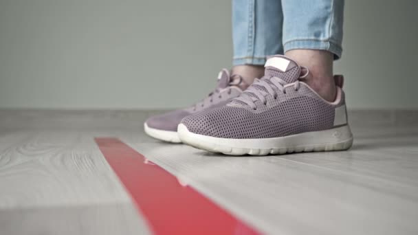 Close up of isolated shoes and older womans legs near a red strip on the floor, waiting and keeping distance while standing in line. During the covid-19. — Stock Video